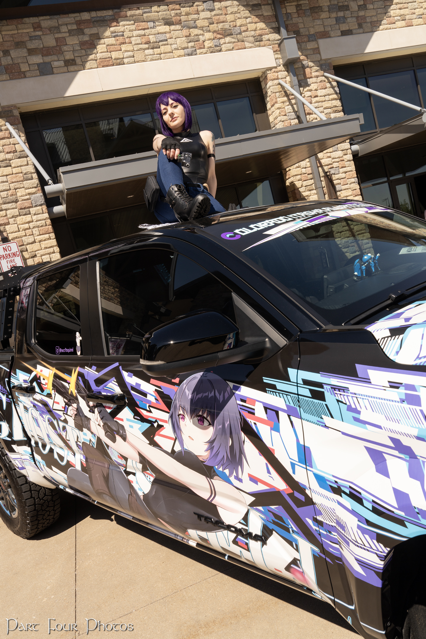 Ghost in the Shell Itasha car with GitS cosplayer sitting on the roof.